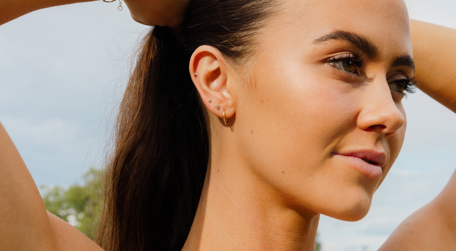 model wearing one endless hoop earring in first piercing, cz trinity live in stud in second piercing and cz prong set stud in third piercing