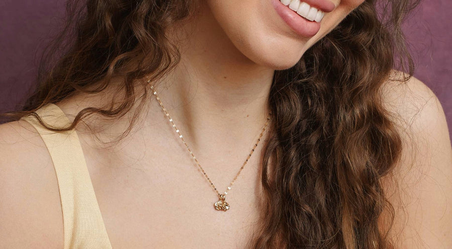 model wearing gold necklace with carnation flower stamp