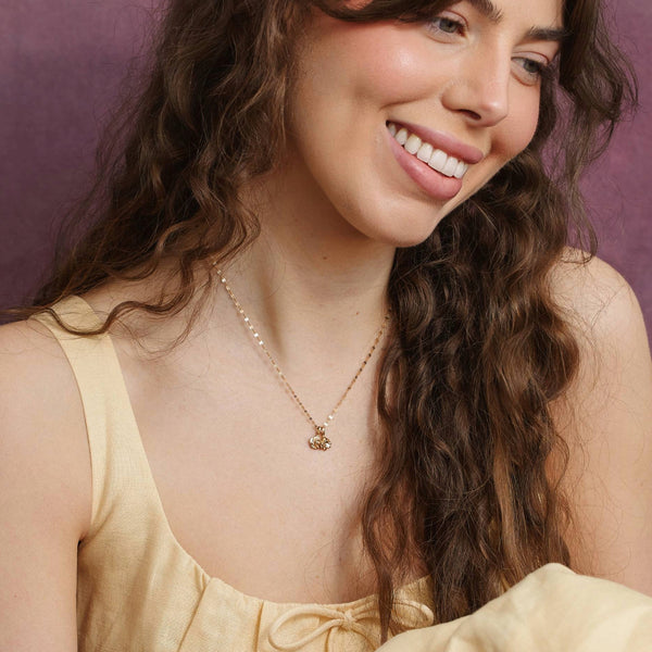 model wearing gold necklace with carnation flower stamp