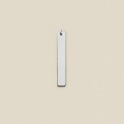 A minimalist, polished silver rectangular bar pendant with a small hanging loop at the top, shown against a solid, warm beige background.