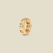 A gold ring charm with multiple bezel set square-cut light green gemstones set side by side to create the band, shown on a solid beige background.