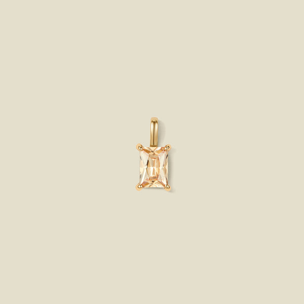 A pendant charm featuring a warm golden baguette-cut prong set gemstone.