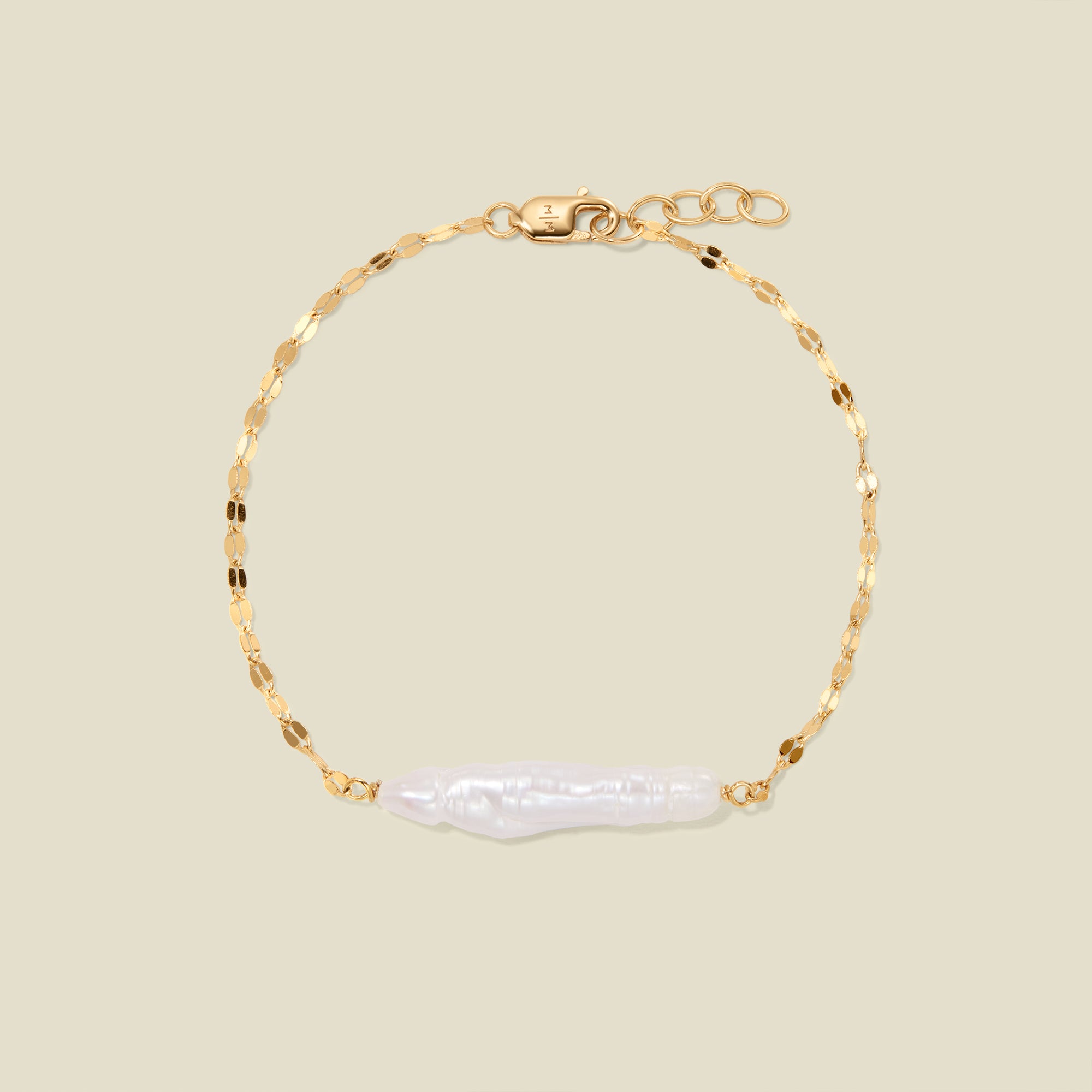 Gold lace chain bracelet with baroque pearl against a plain beige bracelet.