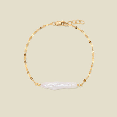 Gold lace chain bracelet with baroque pearl against a plain beige bracelet.
