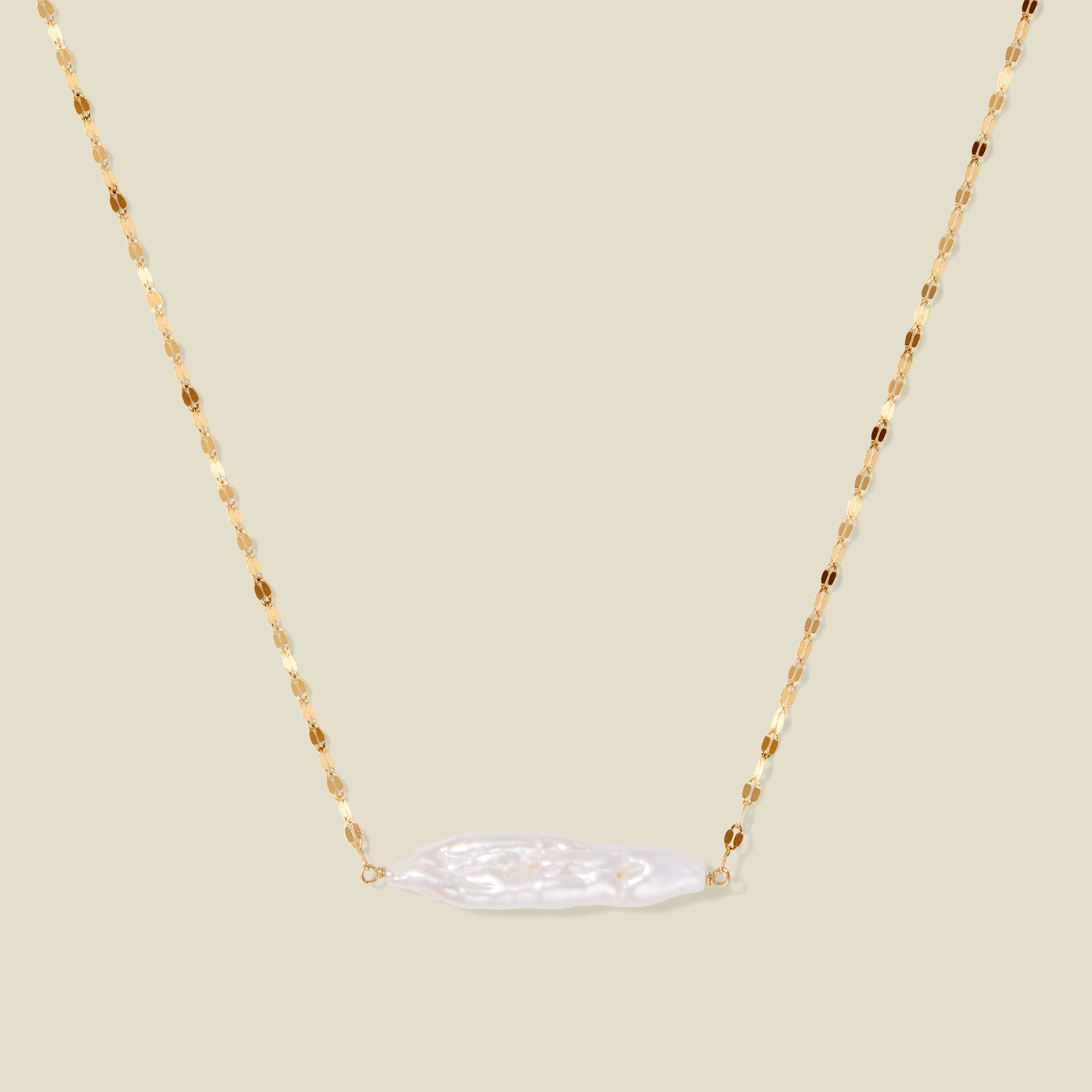Gold lace chain with a baroque pearl pendant, suspended against a neutral background.