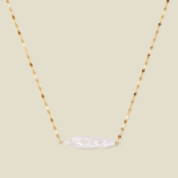 Gold lace chain with a baroque pearl pendant, suspended against a neutral background.