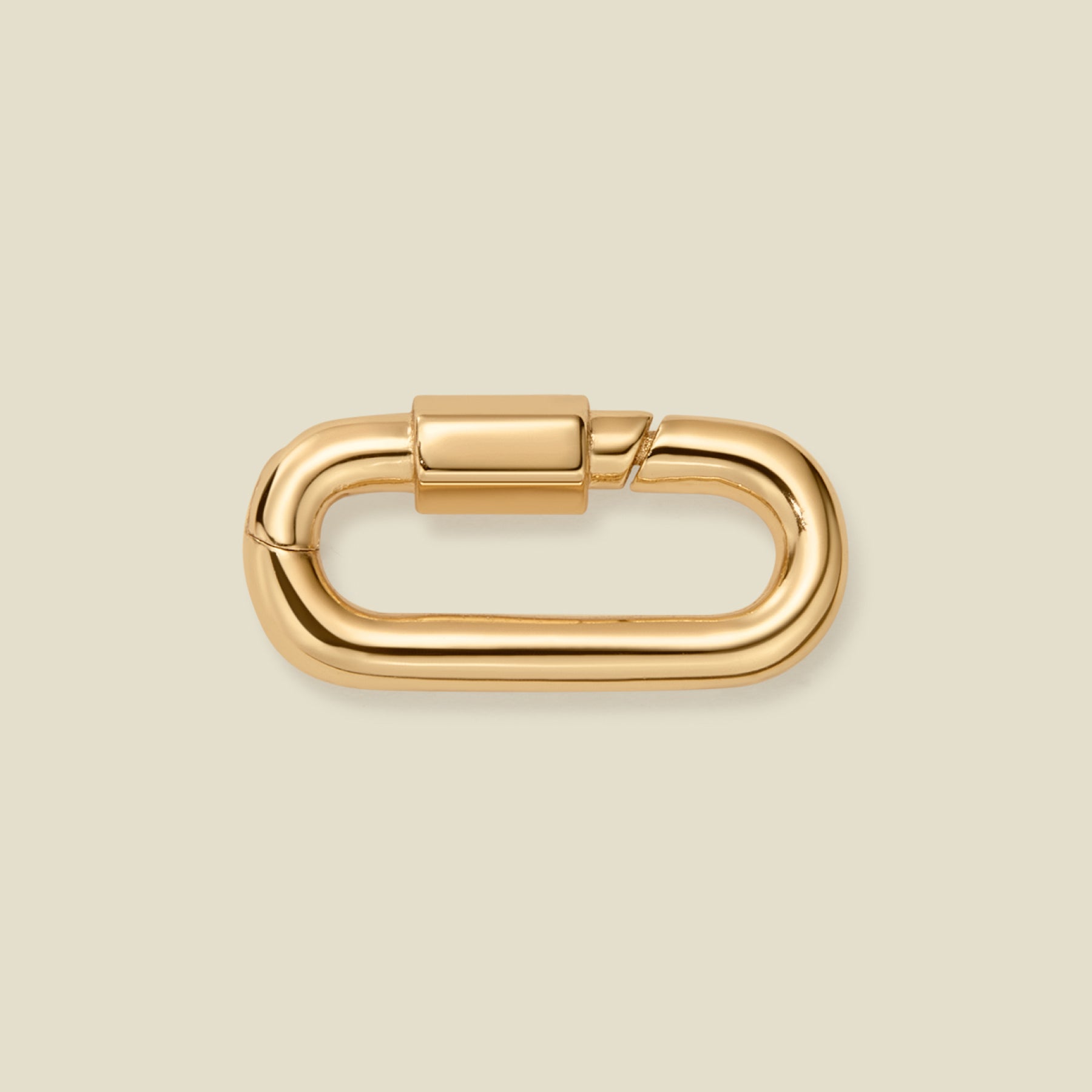 A polished gold metal carabiner clasp with a rounded rectangular shape, shown on a solid light beige background.