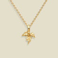 A gold holly flower pendant necklace on a delicate gold chain, presented against a solid light beige background.