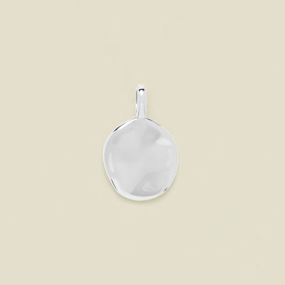 Silver pendant on a beige background