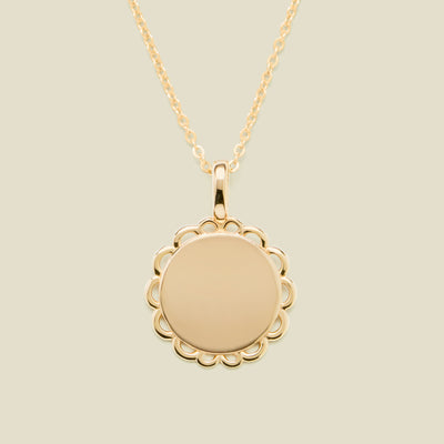 Gold necklace with a round pendant on a beige background