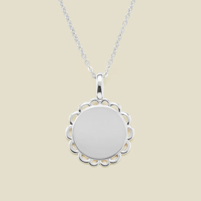 Silver necklace with a round pendant on a beige background