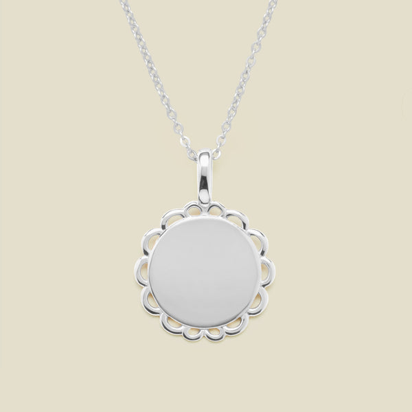 Silver necklace with a round pendant on a beige background