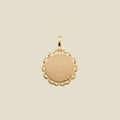 Gold pendant with engraved letter 'E' on a beige background
