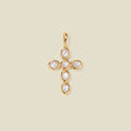 Gold cross pendant made of bezel-set pearl stones, suspended against a neutral background.