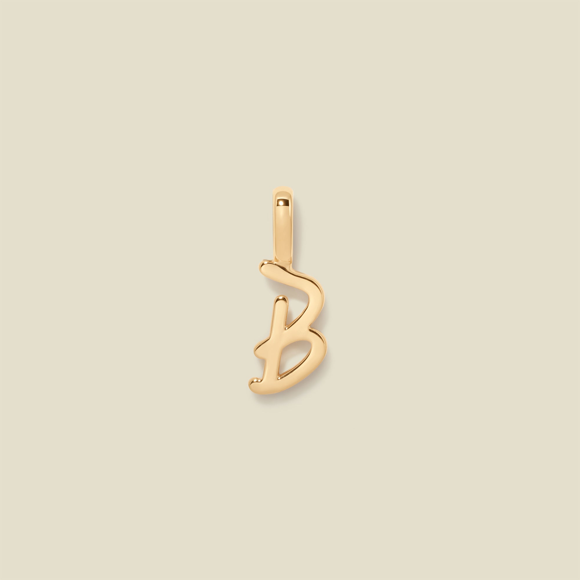 Gold initial "b" charm on a beige background
