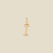 A polished gold initial pendant charm shaped like the letter 'I' in a cursive script, centered on a solid light beige background.