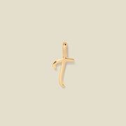 A polished gold initial pendant charm shaped like the letter 'T' in a cursive script, centered on a solid light beige background.
