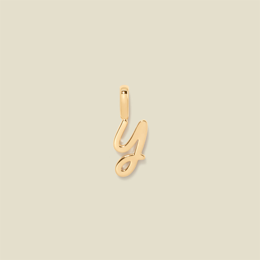 A gold charm letter Y against a neutral background.