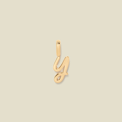 A gold charm letter Y against a neutral background.