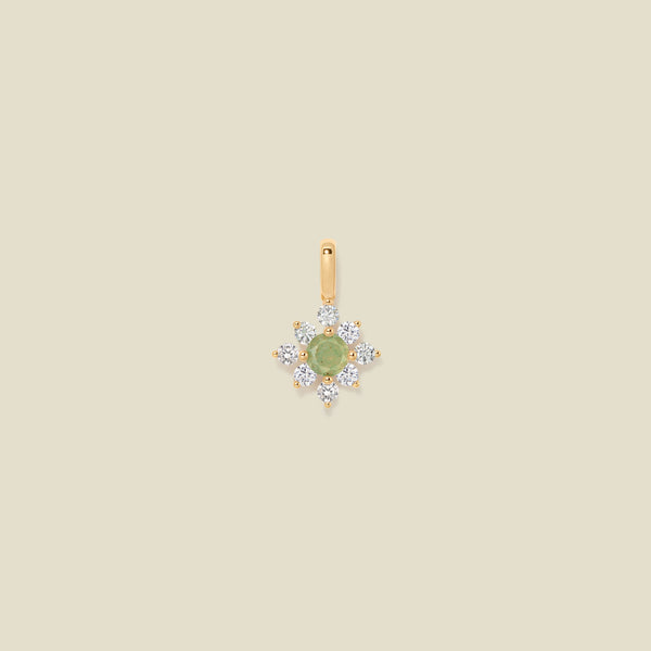 Gold charm with prong-set green and clear stones against a neutral background.