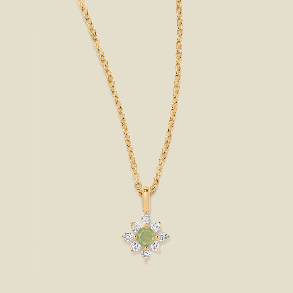 Gold chain with a green prong-set pendant against a neutral backdrop.
