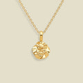 A gold necklace with a small, textured carnation flower pendant, displayed against a solid light beige background.