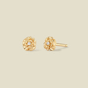 A pair of gold carnation flower stud earrings, each featuring a small round clear gemstone at the center, displayed on a solid light beige background.