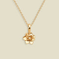A gold pendant necklace featuring a stylized lotus flower charm, suspended from a delicate gold chain against a solid light beige background.