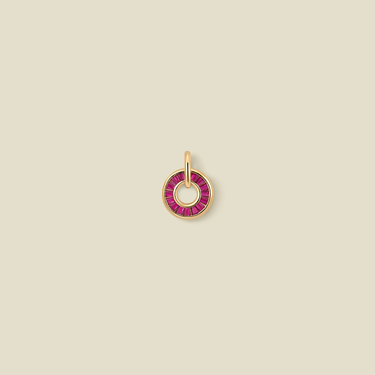 A circular gold pendant featuring red baguette-cut stones around a hollow center, displayed against a solid light beige background.