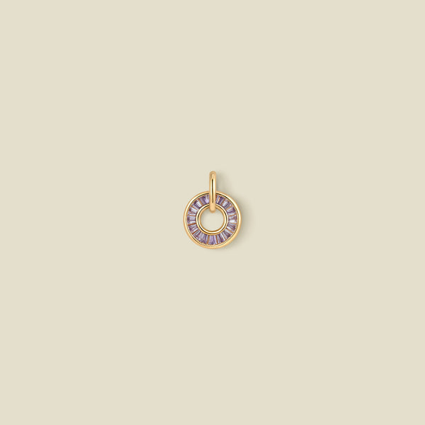 A circular pendant featuring light purple baguette-cut stones around a hollow center, displayed against a solid light beige background.