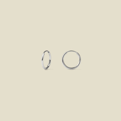 Two silver hoop earrings on a beige background
