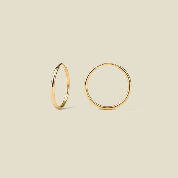Gold hoop earrings on a beige background