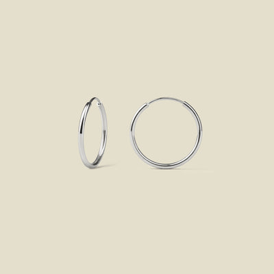 Pair of silver hoop earrings on a beige background