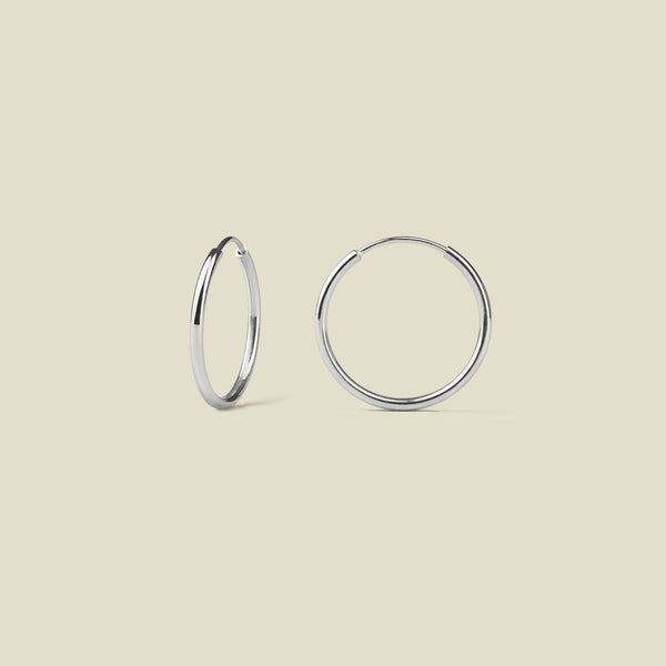 Pair of silver hoop earrings on a beige background