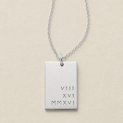 A silver rectangular pendant necklace engraved with the Roman numerals 'VIII', 'XVI', and MMXVI' stacked on the right bottom side of the pendant, on a light beige background.