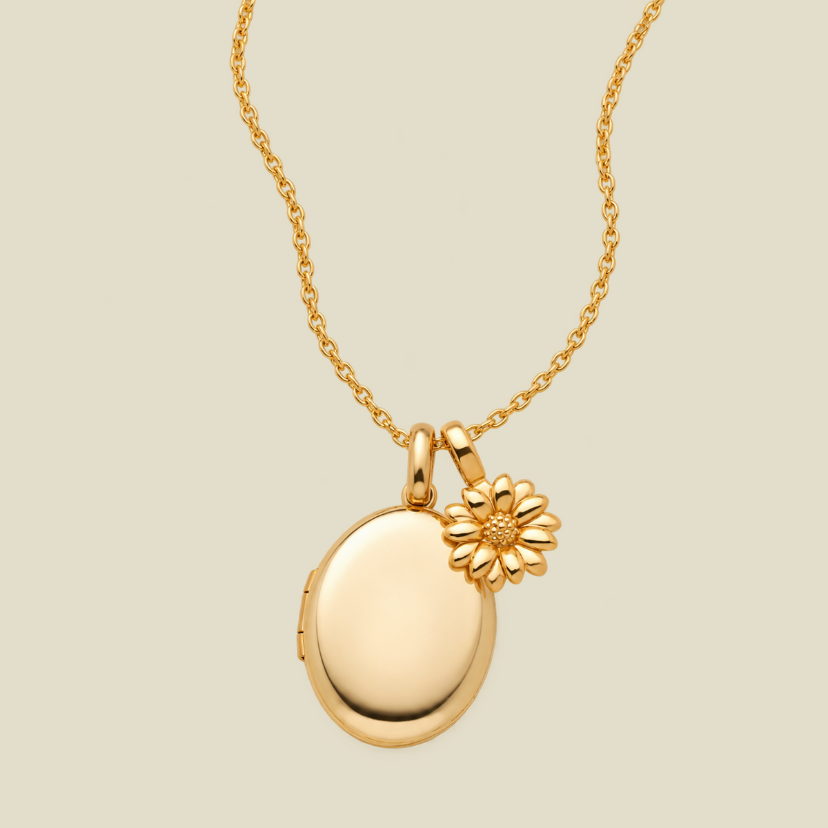 A gold necklace featuring an oval locket pendant with a small daisy charm, displayed on a light beige background.
