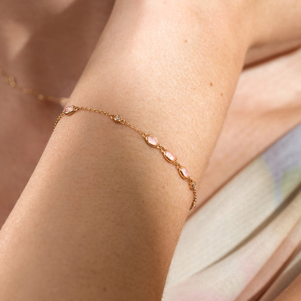 Close-up of a pink bezel-set stone bracelet on a wrist.