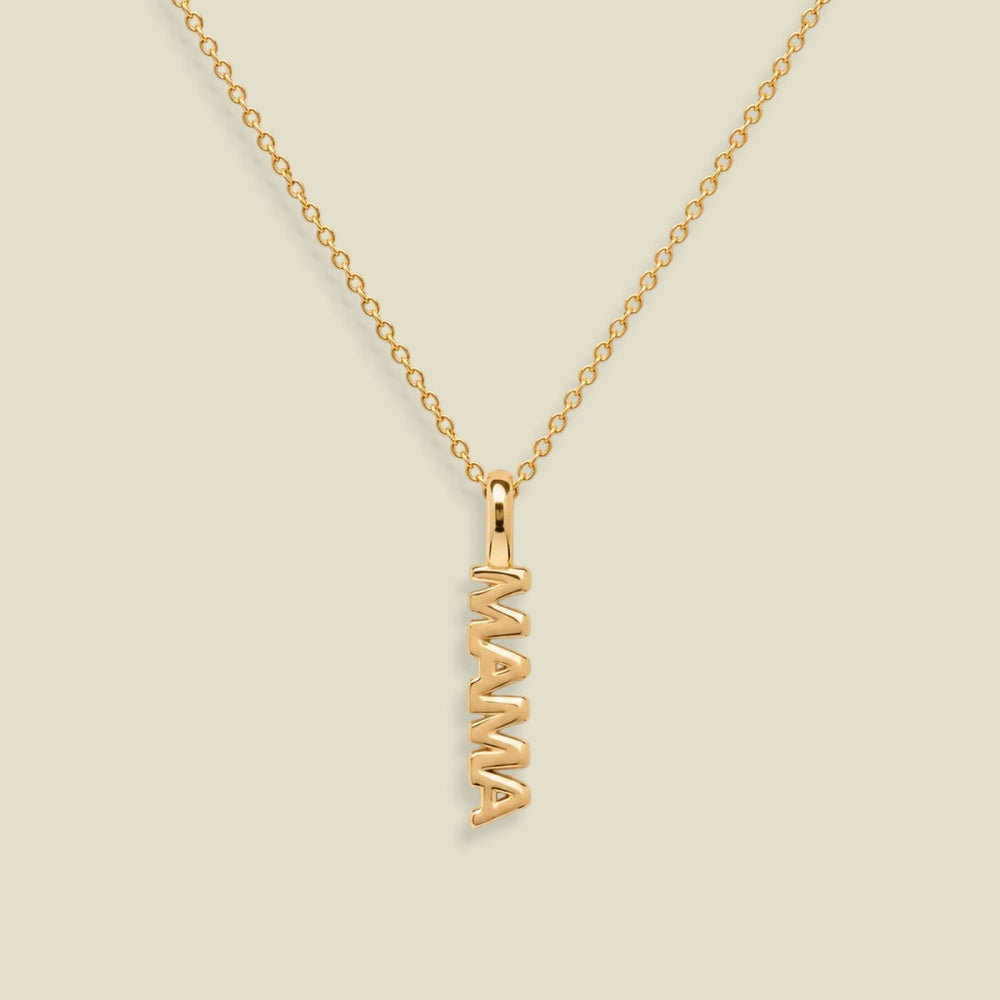 A gold chain necklace with a vertical 'MAMA' nameplate pendant, shown on a solid light beige background.