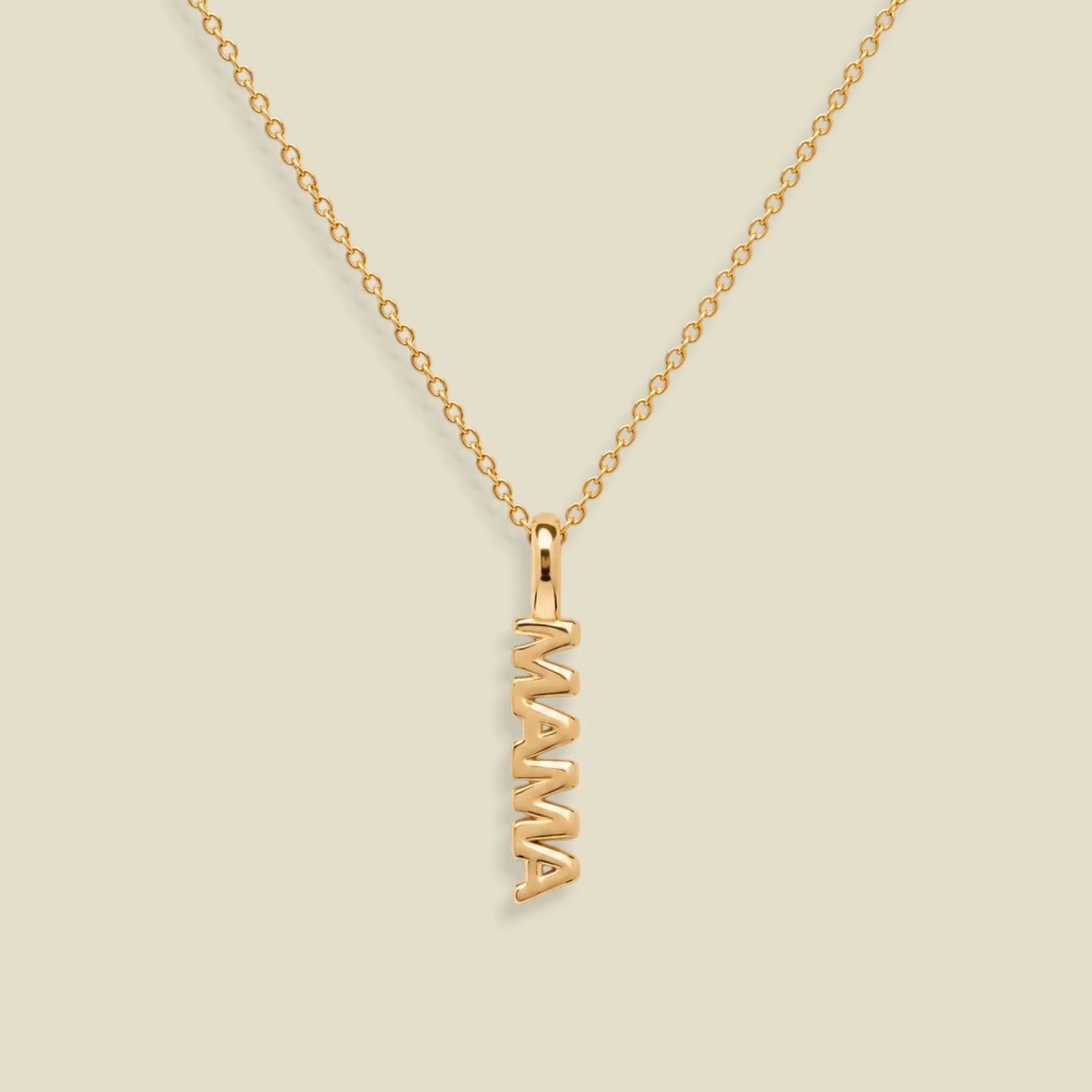 A gold chain necklace with a vertical 'MAMA' nameplate pendant, shown on a solid light beige background.