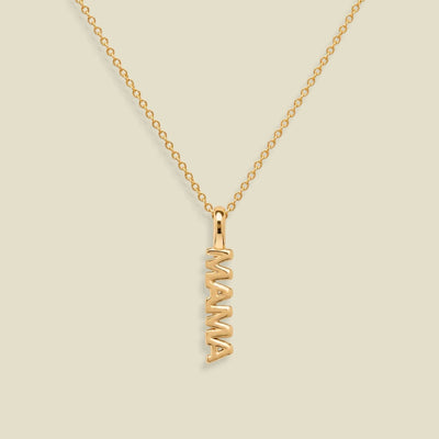 A gold chain necklace with a vertical 'MAMA' nameplate pendant, shown on a solid light beige background.