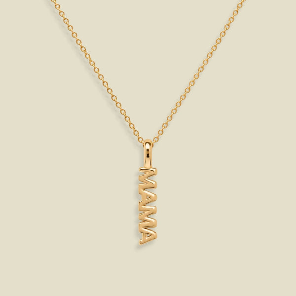 A gold chain necklace with a vertical 'MAMA' nameplate pendant, shown on a solid light beige background.