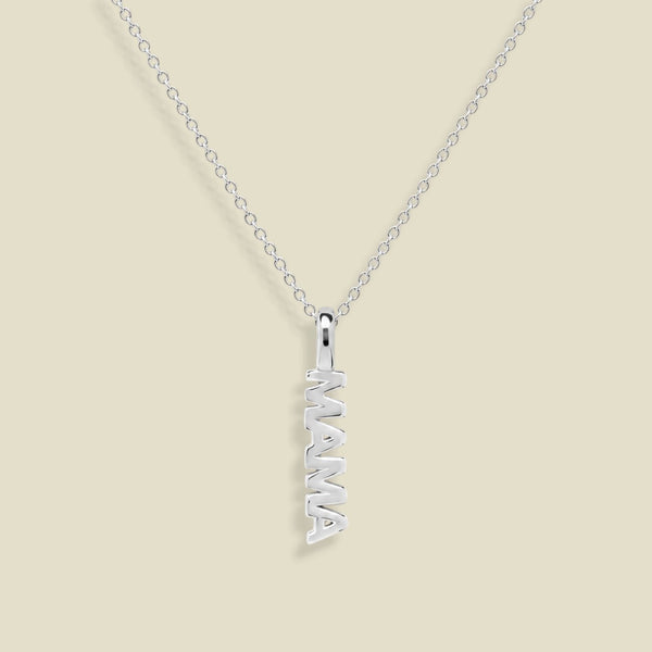 A silver name necklace featuring a vertical pendant spelling 'MAMA' in an openwork design, suspended from a delicate silver cable chain against a solid beige background.