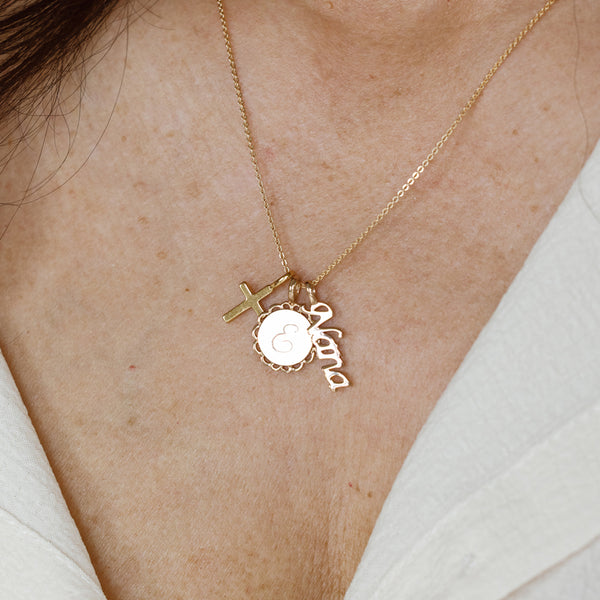 Gold necklace with cross, disc and "Nana" charms on a model