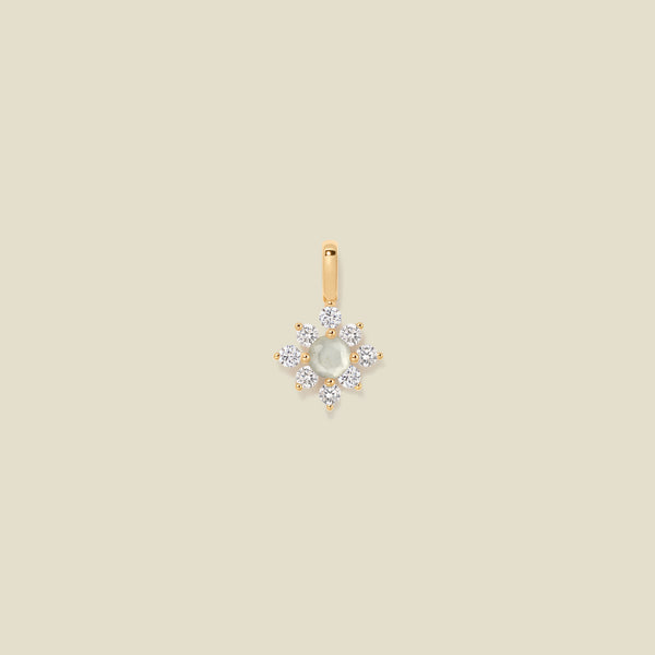 Gold charm with prong-set white and clear stones against a neutral background.