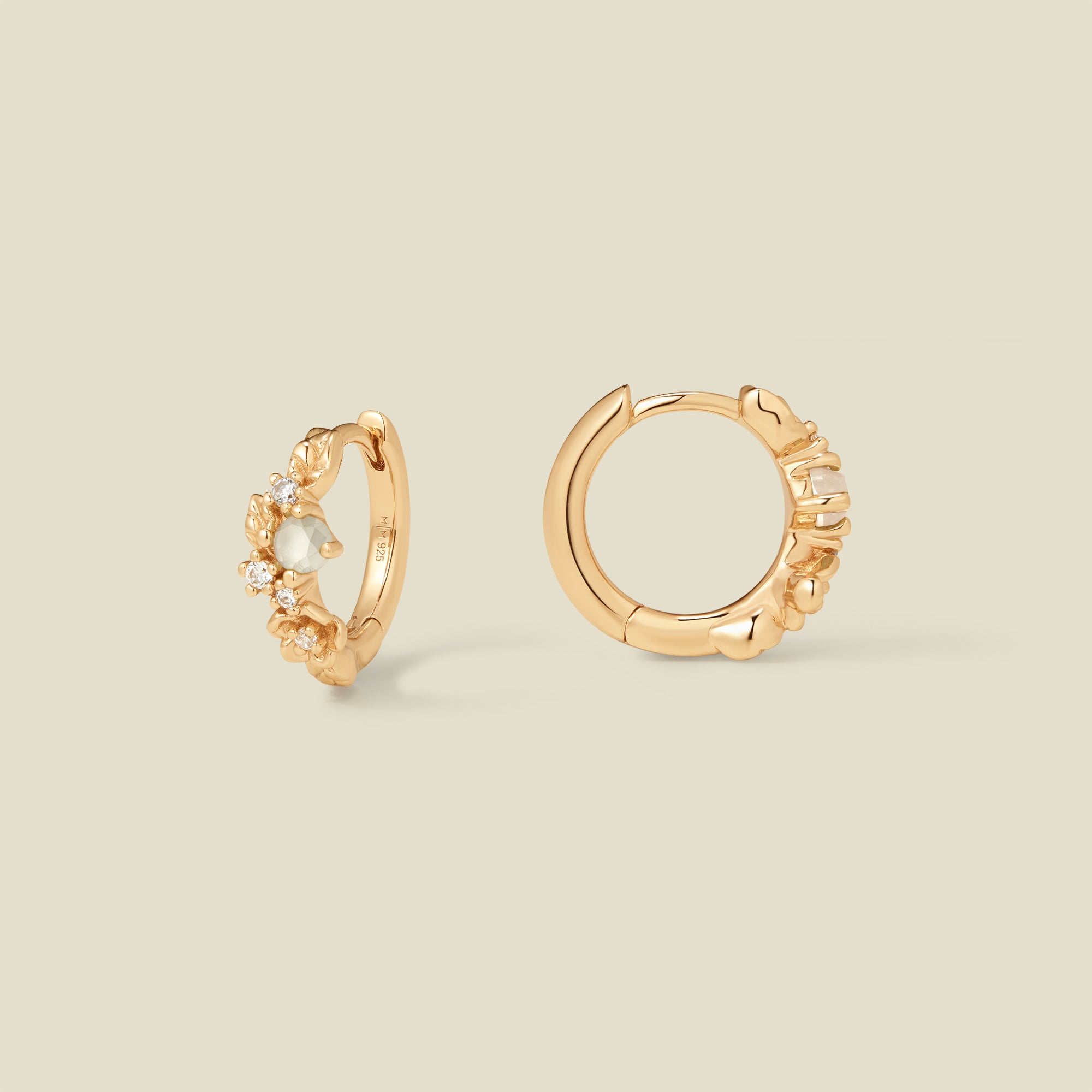 Gold hoop earrings with prong-set white and clear stones against a neutral background.