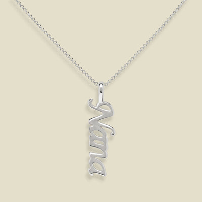A silver nameplate necklace spelling 'Nana' in a cursive font, hanging vertically from a delicate silver chain against a solid beige background.