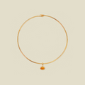A thin gold wire choker necklace with a small oval amber gemstone pendant, displayed on a solid light beige background.