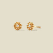 A pair of gold chrysanthemum flower stud earrings, each featuring a small round clear gemstone at the center, displayed on a solid light beige background.