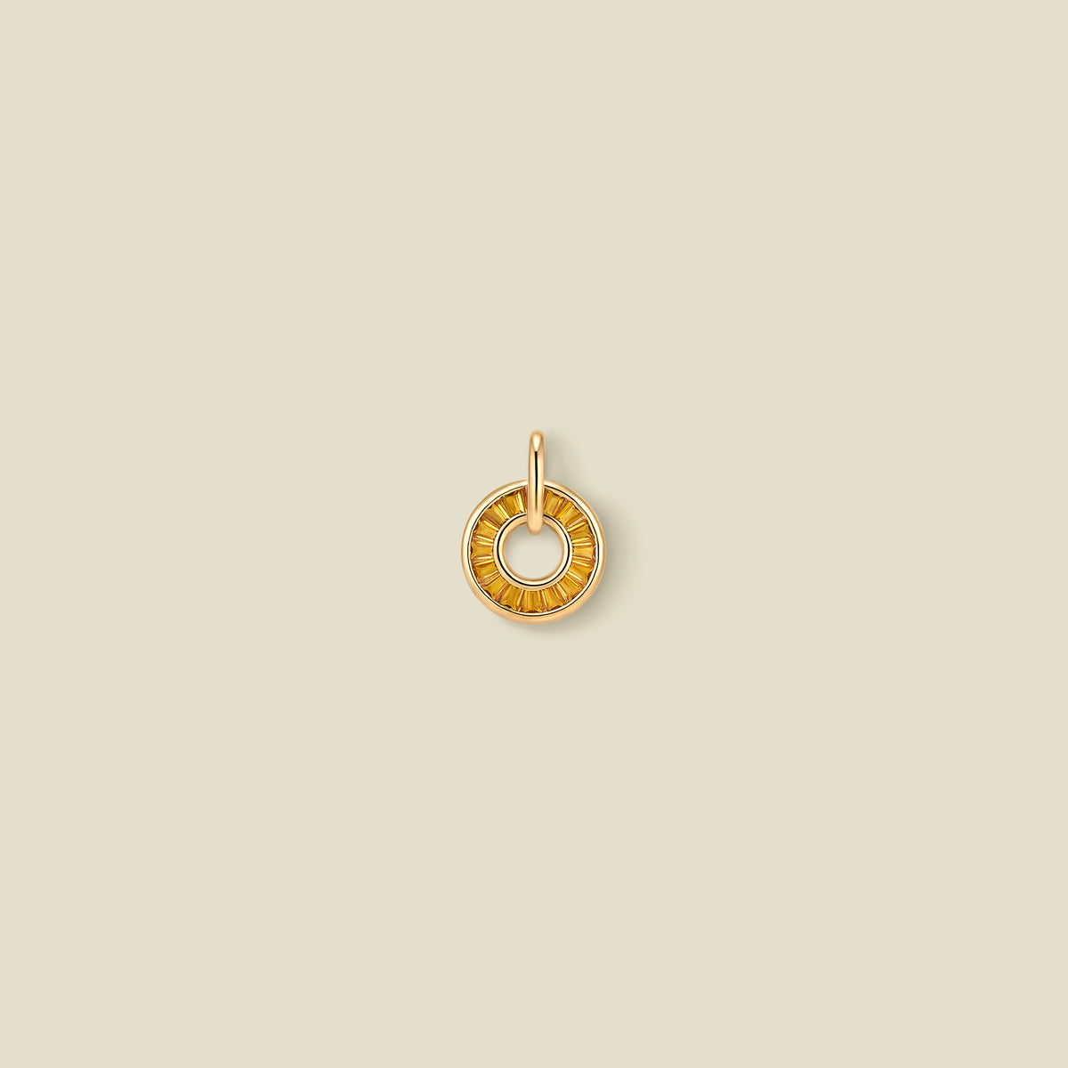 A gold circular pendant featuring golden yellow baguette-cut stones around a hollow center, displayed against a solid light beige background.