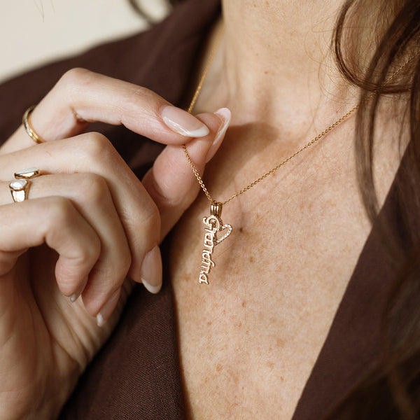 Gold necklace with 'Grandma' pendant being adjusted on a person's neck.